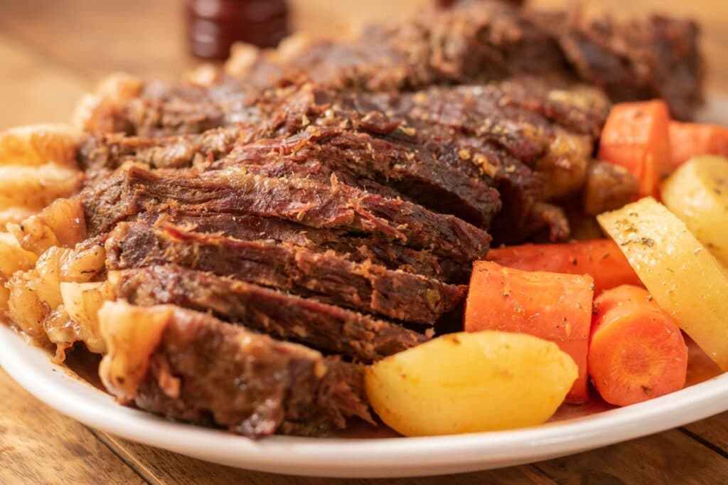 Carne de panela macia servida com cenoura e batata em um prato branco