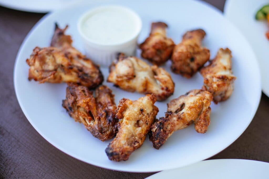 Asinhas de frango crocantes servidas em um prato branco com molho