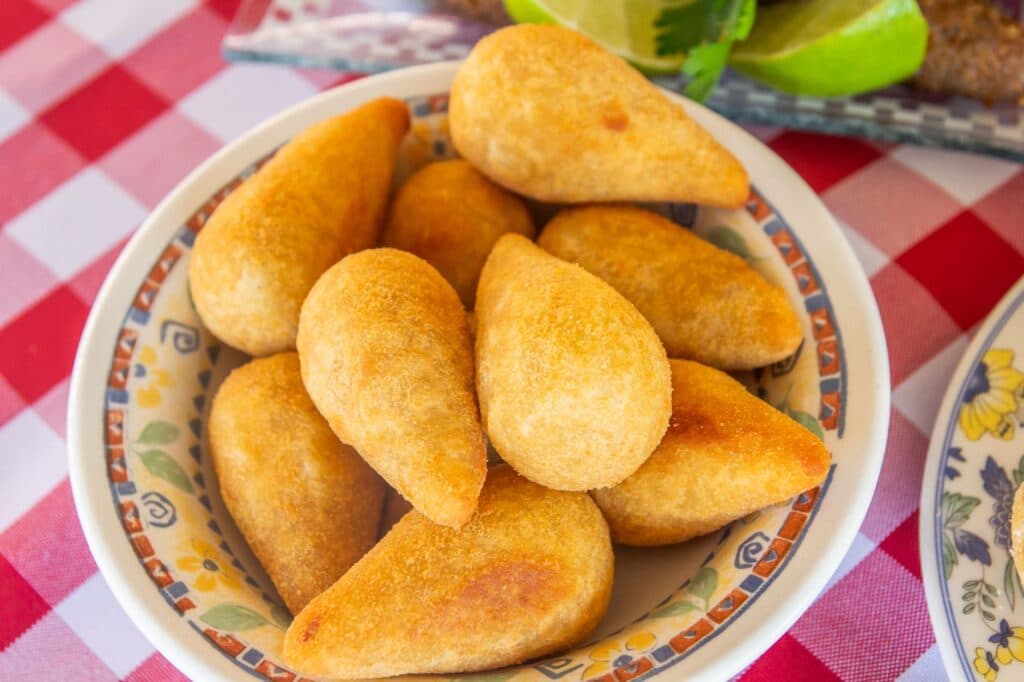 Prato de coxinhas douradas sobre uma toalha xadrez