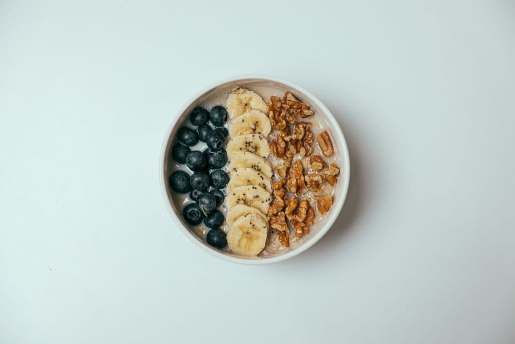 Tigela de mingau de aveia com banana, mirtilos e nozes por cima