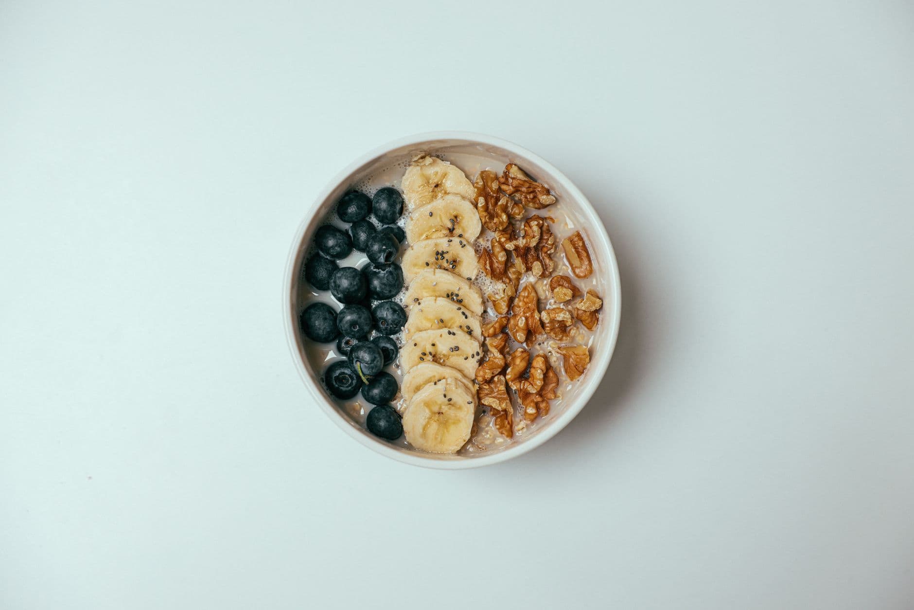 Tigela de mingau de aveia com banana, mirtilos e nozes por cima